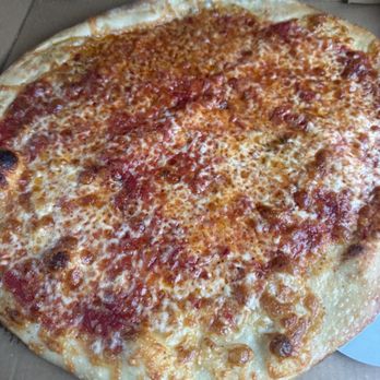 OTTO - A cheese pizza with a slightly uneven, golden-brown crust is displayed inside a cardboard pizza box. The pizza is topped with melted cheese and tomato sauce, with some areas showing more cheese coverage than others. The pizza appears to be freshly baked, with some darker spots on the crust indicating charring from baking. - Pizza Near Me - Saco, Maine