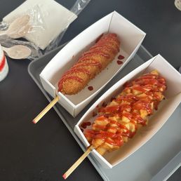 korean corn dog, half and half, one with just ketchup and one with ketchup and potatoes