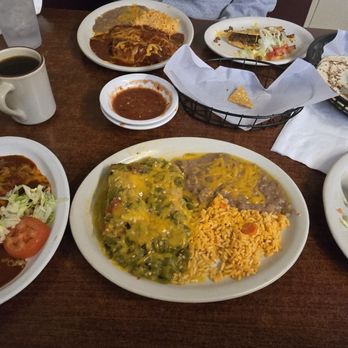 El Comal - A selection of Mexican food including enchiladas, rice, and a taco, with a cup of coffee and salsa on a wooden table. - Mexican Near Me - Santa Fe, New Mexico