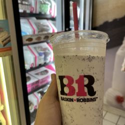Baskin Robbins - Baskin Robbins milkshake in front of a freezer full of ice cream cake.