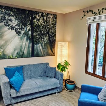 Wellspring Midwifery - Photo of the interior of Wellspring Midwifery's office: A gray couch, large photo, lamp, plant, and blue chair with a window. - Prenatal/Perinatal Care Near Me - Federal Way, Washington Wellspring Midwifery - Photo of the interior of Wellspring Midwifery's office: A gray couch, large photo, lamp, plant, and blue chair with a window. - Prenatal/Perinatal Care Near Me - Federal Way, Washington