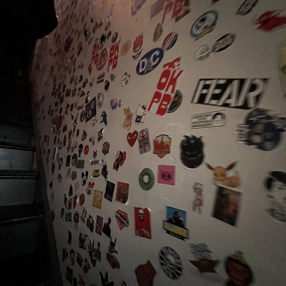 OKPB - Stickers adorn the wall as you walk up to the bar space - Cocktail Bars Near Me - Washington, DC, District of Columbia OKPB - Stickers adorn the wall as you walk up to the bar space - Cocktail Bars Near Me - Washington, DC, District of Columbia