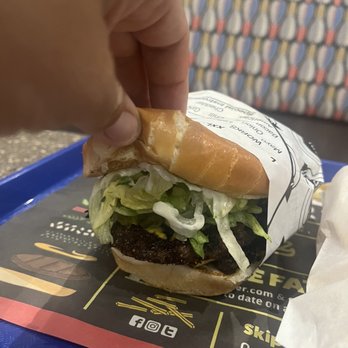 Fatburger - a hand grabbing a hamburger from a tray - Juice Bars & Smoothies Near Me - Albuquerque, New Mexico