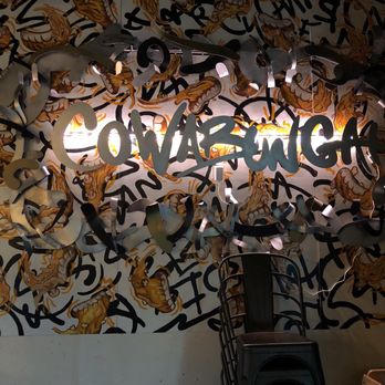 Cowabunga - A wall features a neon sign that says 'COWABUNGA' with a background mural of tiger faces and abstract black lines. - Pizza Near Me - Hamilton, Ontario