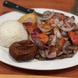 Sol Inka - Bistec a La Chorillana is a psteak with sauteed onions and tomatoes served with a fried potato half, fried roll and white rice