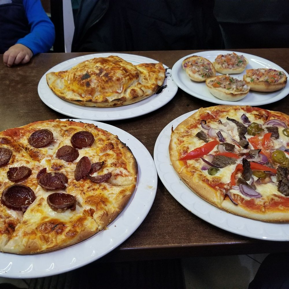 Pizza El Fredo - Counter clockwise from the front left: Garlic pizza, Latino, Brushetta, and Calzone. - Italian Near Me - Berlin, BE Pizza El Fredo - Counter clockwise from the front left: Garlic pizza, Latino, Brushetta, and Calzone. - Italian Near Me - Berlin, BE