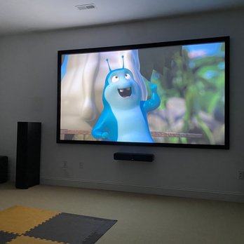 PowerHouseAV - The home theater after they finished their work - A home theater room features a large flat-screen TV showing an animated character, with two tall speakers on either side and a small subwoofer on the left. - Home Automation Near Me - Arlington, Virginia