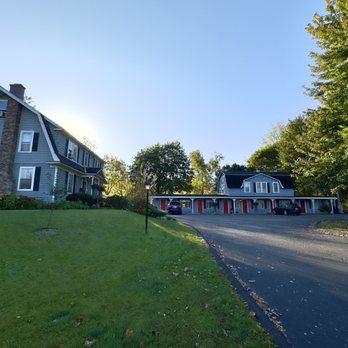 Grayhaven Motel - A large house with multiple windows and a chimney is situated on a grassy lawn, with a paved driveway leading to a garage with red doors, surrounded by trees. - Hotels Near Me - Ithaca, New York