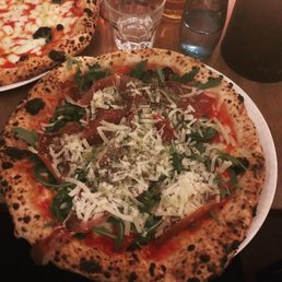 Pizza with prosciutto, arugula,parmesan,and fresh mozzarella.