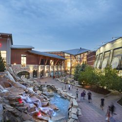 FlatIron Crossing - Shoppers walk beside a cascading waterfall near the FlatIron Crossing entrance at dusk.