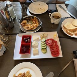 Tradicional Turkish breakfast menemen with soğuk sausage variety of cheese olives and toast with çay (Turkish tea)