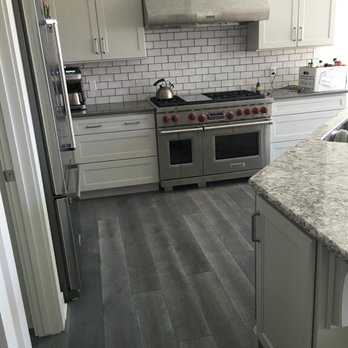 Floor It - a kitchen with white cabinets and stainless steel appliances - Flooring Near Me Floor It - a kitchen with white cabinets and stainless steel appliances - Flooring Near Me