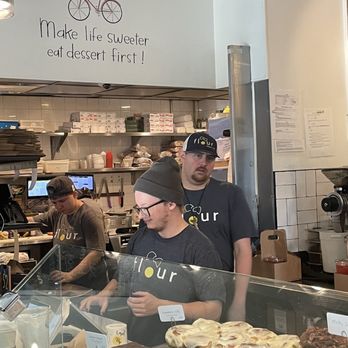 Flour Bakery + Cafe - Staff man the till under a slogan "Make life sweeter, eat dessert first!" - Bakeries Near Me - Boston, Massachusetts