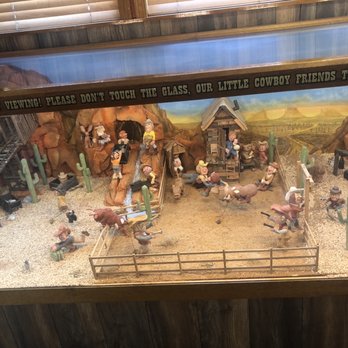 Charcoal Corral - Awesome animated display - A detailed miniature display depicts a cowboy scene with figurines, cacti, a small house, and a painted desert background, enclosed in a glass case. - Pizza Near Me - Perry, New York