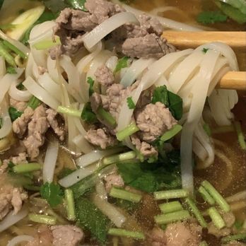 Pho 98 - A close-up of Vietnamese pho featuring rice noodles, ground meat, and chopped herbs in a clear broth. - Vietnamese Near Me - Chantilly, Virginia