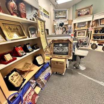 Moody design - The image shows the interior of a retail store with shelves displaying framed artwork, jewelry, and decorative objects. The store has a carpeted floor, ceiling lights, and various items arranged on shelves and tables. Some items are in boxes or display cases, and there are signs and decorative pieces visible throughout the space. - Gift Shops Near Me - Edison, New Jersey
