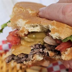 Absolutely Delicious Bar and Grill - Close-up of the Hamburger being held and getting ready to eat.