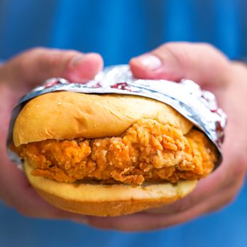 Champs Chicken - hands holding a sandwich wrapped in foil - Chicken Shop Near Me - Calhan, Colorado