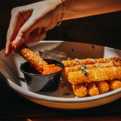 Miller's Ale House - A plate of Mozzarella Sticks dipping in our warm marinara sauce