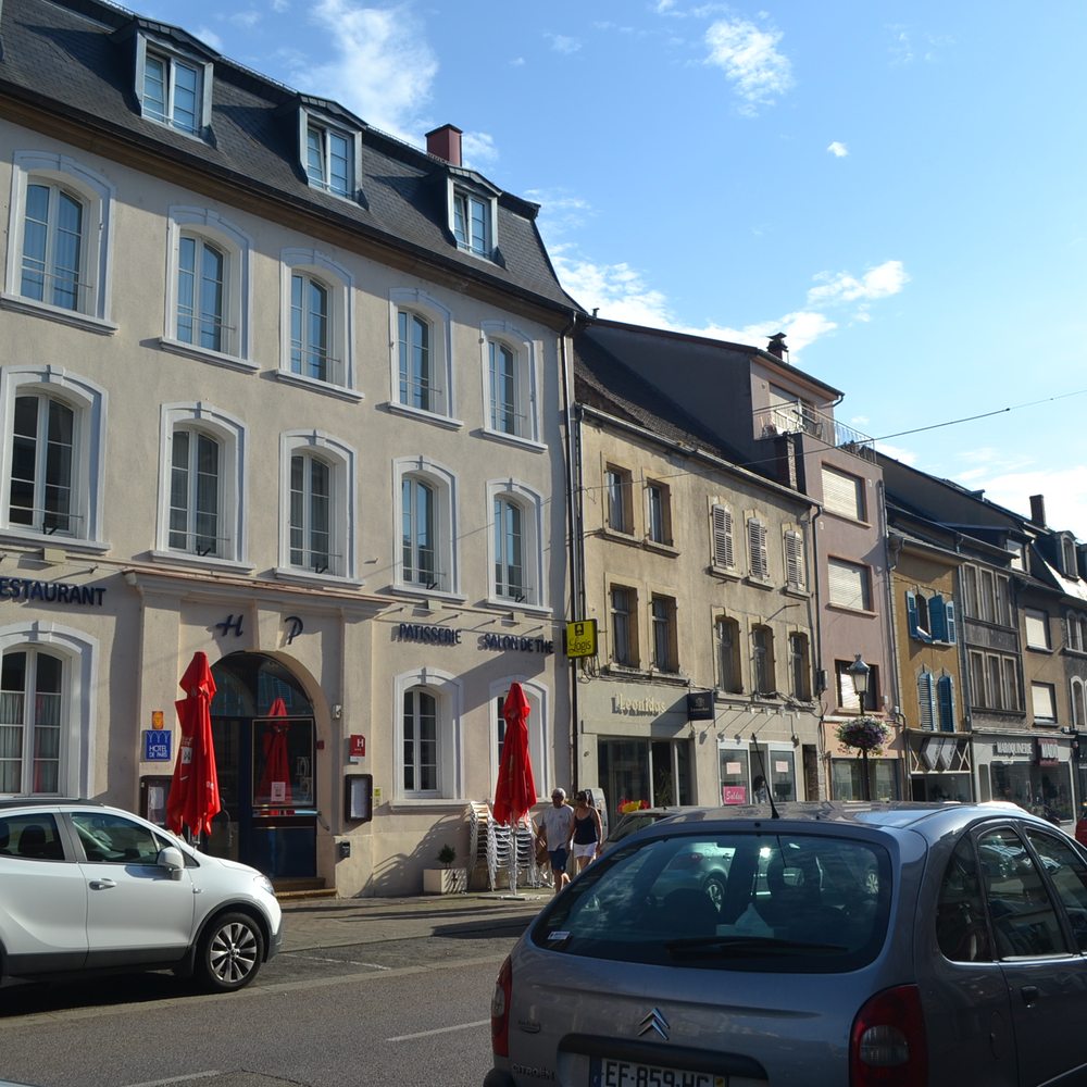Hôtel Restaurant de Paris - Hotel on left by red umbrella tables. - French Near Me - Saint-Avold, 57