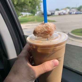 35th & Coffee - a hand holding a cup of coffee with a donut on top - Coffee & Tea Near Me - Menominee, Michigan 35th & Coffee - a hand holding a cup of coffee with a donut on top - Coffee & Tea Near Me - Menominee, Michigan