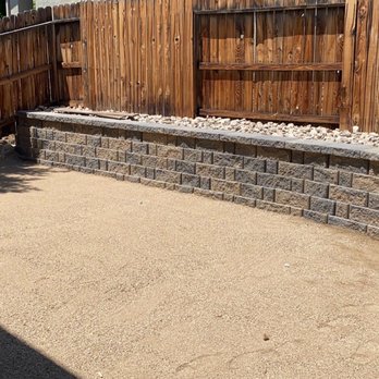 The Lawn Salon - a wooden fence and a stone wall - Landscaping Near Me