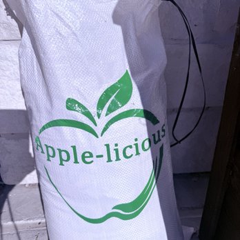 Apple-licious - A white woven bag features a green apple outline and the text 'Apple-licious' printed across it, with a black drawstring closure. - Bakeries Near Me - Spring, Texas