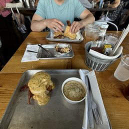 Breakfast biscuit with egg, bacon and gravy with a side of grits.
