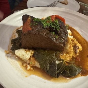 Zinnia - A dish featuring braised beef served with mashed potatoes, leafy greens, and gravy, on a white plate at a restaurant. - Cocktail Bars Near Me - Silver Spring, Maryland