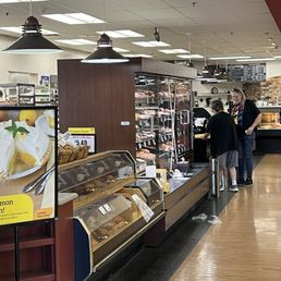 New display hiding the staff from view. - Inside Bashas' supermarket, bakery display cases hold baked goods, with customers shopping and staff behind the counter.