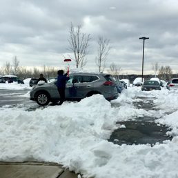 Employees clearing snow from guests' cars