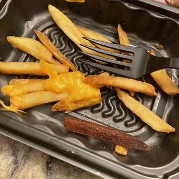 Wendy's - a tray of fries and a fork - The image shows a black plastic tray with a few French fries, some melted cheese, and a single fry. A black fork rests on the tray, and the tray is placed on a speckled countertop. The tray appears to have been used for a meal, with some food remnants remaining. - Fast Food Near Me - Howell, New Jersey