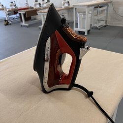 Made Stitch - Ironing tables, with a view of some of the machines.