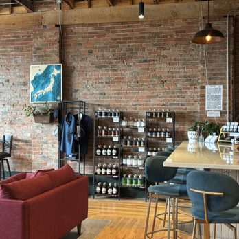 Method & Muse Spirits - A cafe interior featuring exposed brick walls, a bar counter with seating, and shelves with jars and plants. - Distilleries Near Me - Arvada, Colorado
