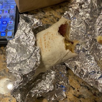 Inxpot - a burrito wrapped in aluminum foil - A breakfast burrito with a bite taken out, wrapped in aluminum foil, resting on a granite countertop with a smartphone nearby. - Coffee & Tea Near Me - Keystone, Colorado