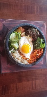 Photo of Mr bibi - Oceanside, CA, US. The hot stone bibimbap with beef and a sunny side egg. Vegetables are cucumbers, beansprouts, kale, carrots and more.