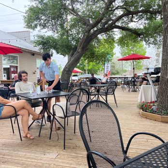Grapevine On Main - a group of people sitting at outdoor tables - Wine Bars Near Me - Chappell Hill, Texas