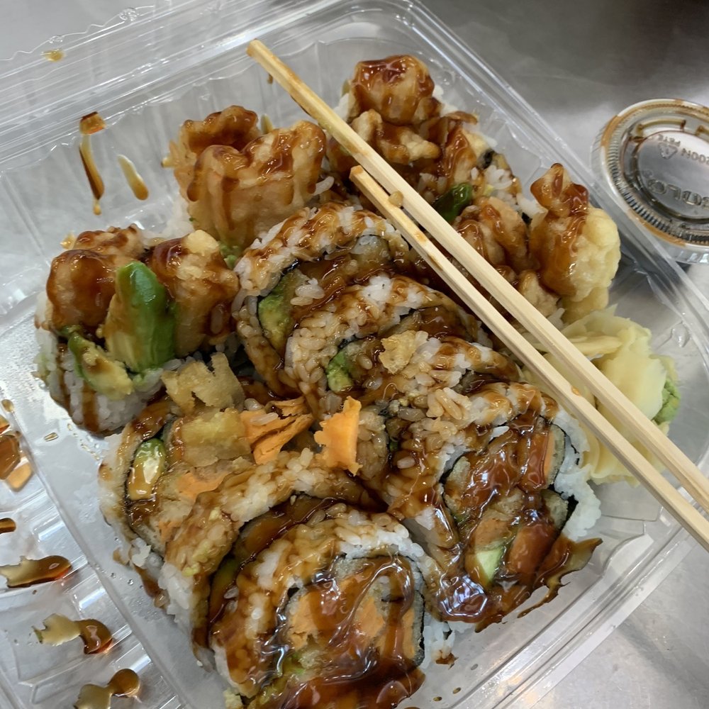Sushi.Com - a close up of a container of sushi with chopsticks - Sushi Bars Near Me - Hicksville, New York Sushi.Com - a close up of a container of sushi with chopsticks - Sushi Bars Near Me - Hicksville, New York