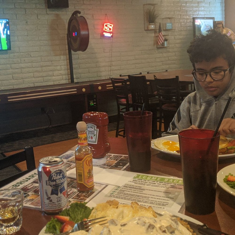 Bogeys Grill - a young man eating a burger - Sports Bars Near Me - Tempe, Arizona