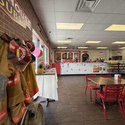 Firehouse Subs - Fireman's jackets and hoses, catering table and hot sauce bar. Front counter where the magic happens. Subs served hot! Julie A
