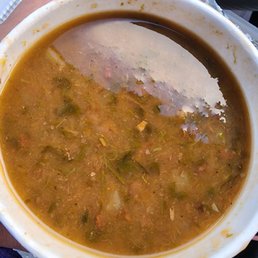 Charro Beans - A close-up of a bowl containing charro beans, with herbs and a broth, likely served at a Mexican restaurant.