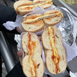 Sesame bagels with egg, ketchup, salt pepper and one of them has sausage too Sesame bagels with egg, ketchup, salt pepper and one of them has sausage too