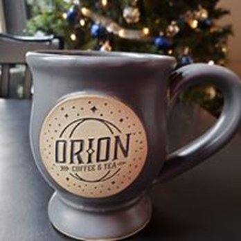 Orion Coffee And Tea - a coffee mug on a table with a christmas tree in the background - Coffee & Tea Near Me - Jamestown, Ohio Orion Coffee And Tea - a coffee mug on a table with a christmas tree in the background - Coffee & Tea Near Me - Jamestown, Ohio