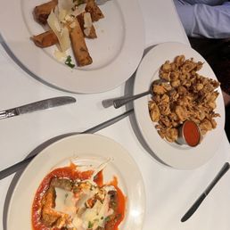 Chicken Parmigiana - Three plates of Indian food are on a white table: samosas with cheese shavings, fried cauliflower with sauce, and a curry dish with cheese and sauce.
