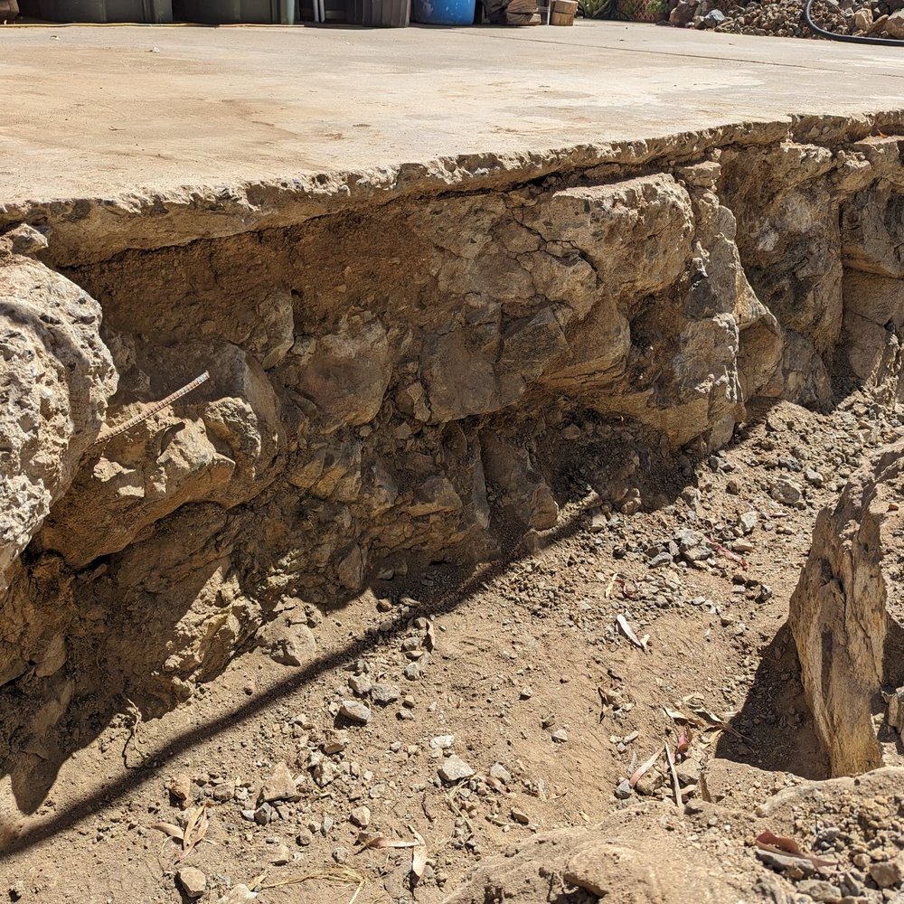 Tom Masonry - Damage inadvertently caused by an excavator with a hammer when breaking through very hard rock to dig a trench for a French drain. - Masonry/Concrete Near Me