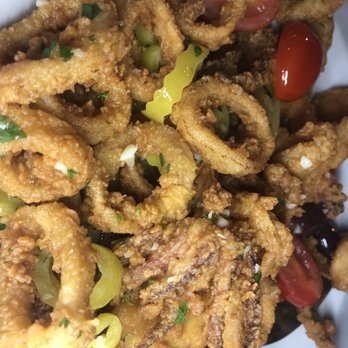 Teddy G's - Calamari - A plate of fried calamari rings garnished with cherry tomatoes, chopped herbs, and lemon wedges, served at Teddy G's restaurant. - Pubs Near Me - Sturbridge, Massachusetts