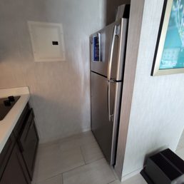 full size fridge, dishwasher, sink and stove. There are cabinets on the top filled with eating utensils.