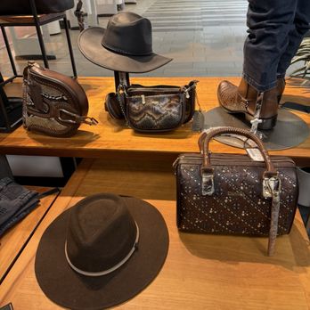 Cuadra - A retail store display features handbags, hats, and boots arranged on wooden tables and shelves, with a modern interior background. - Shoe Stores Near Me - Austin, Texas