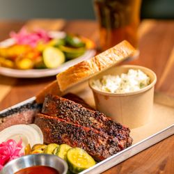 Founding Farmers - Alexandria - A metal BBQ tray with Sweet Heat St. Louis Spareribs, white bread, coleslaw, pickled vegetables, and Joe's BBQ sauce, served ...