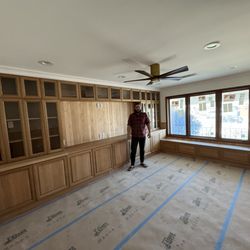 Spacious living room with custom built-in wooden cabinets and large windows. Ideal for elegant and functional home interiors.